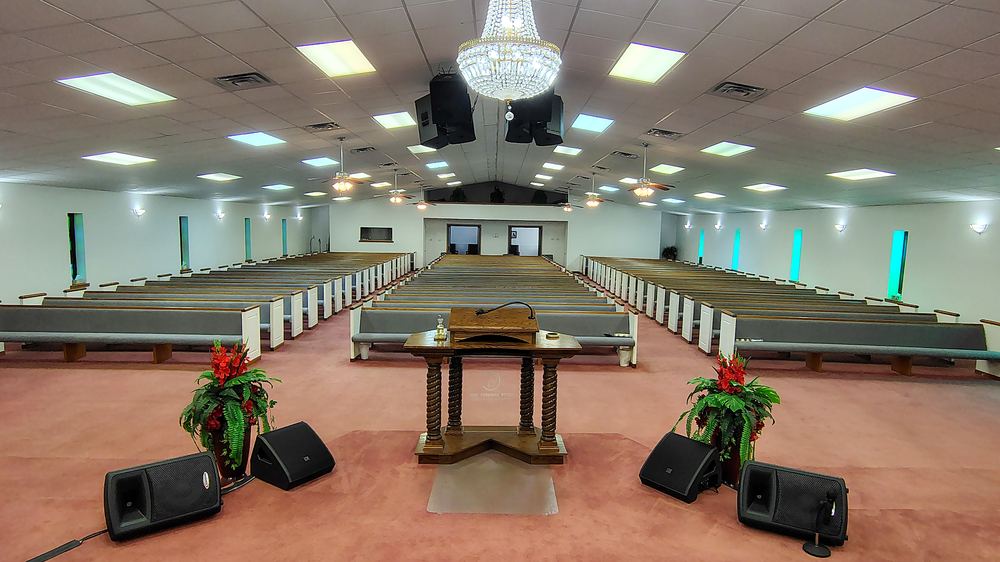 The sanctuary of Lakeview Community Temple seen down the center aisle, with the communion table and chandelier